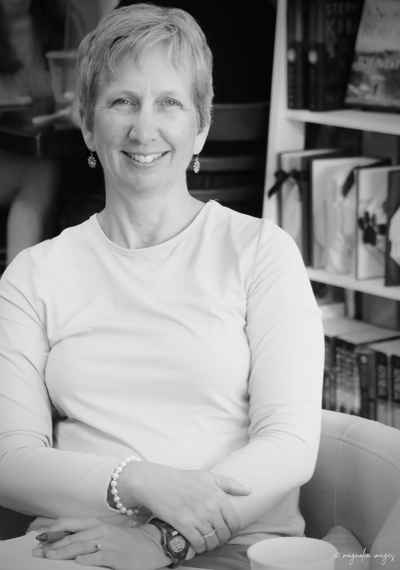 black and white image of Amanda sitting in front of a wall of books smiling