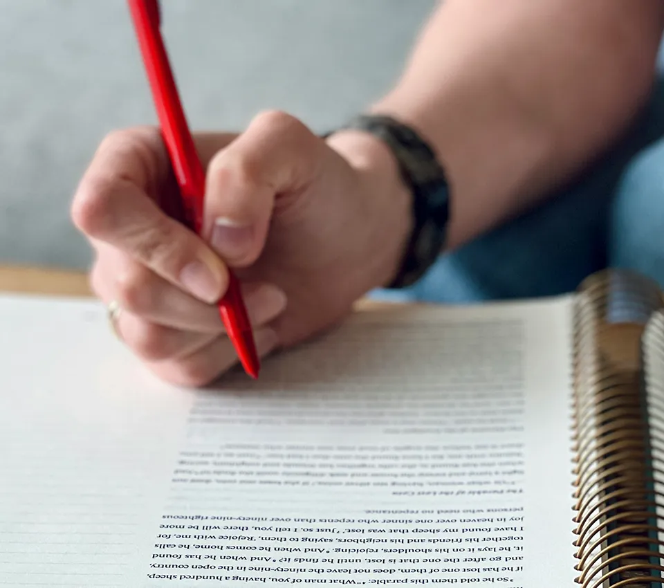 hand holding red pen writing on document