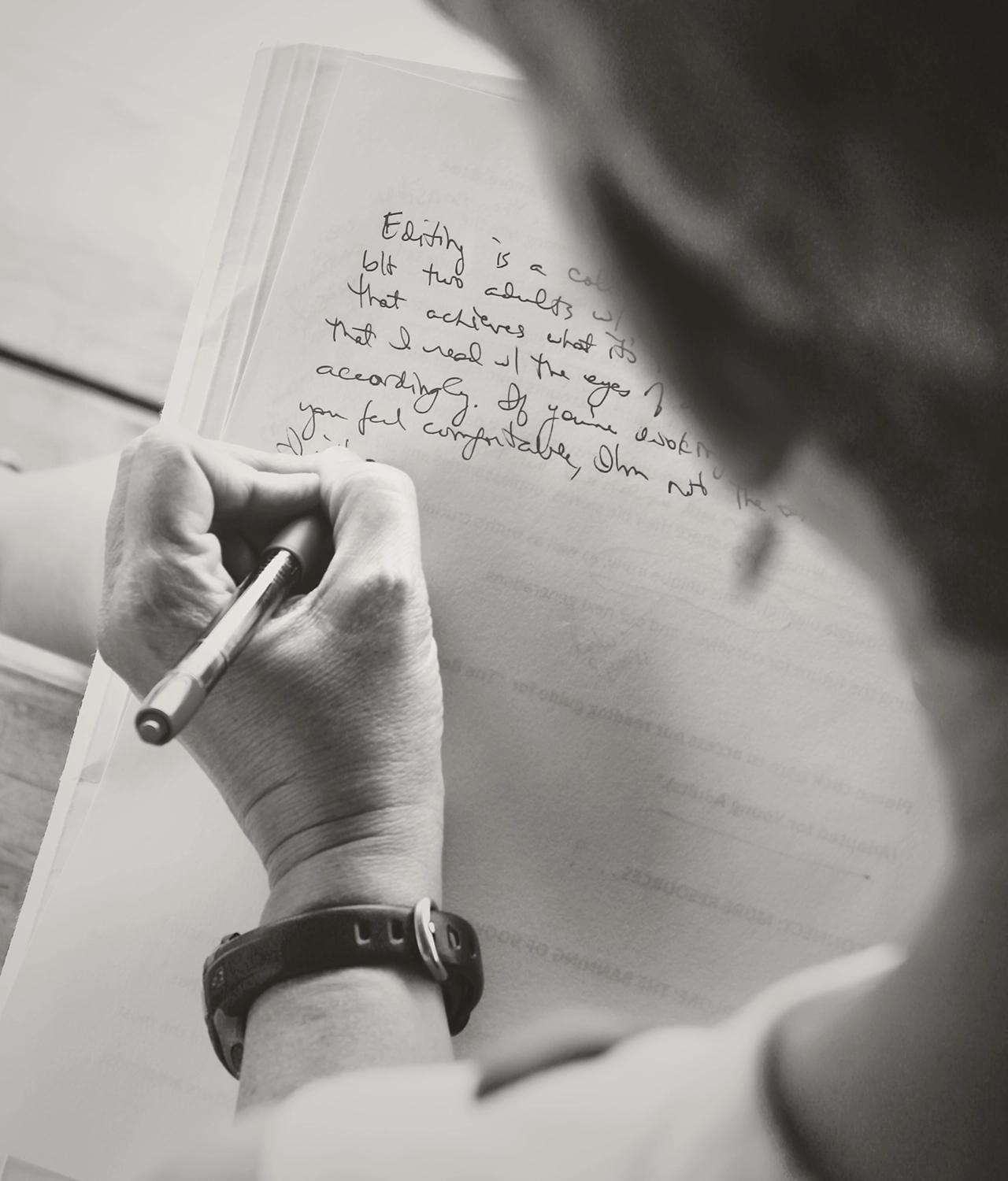 black and white image looking over the shoulder of person writing about editing