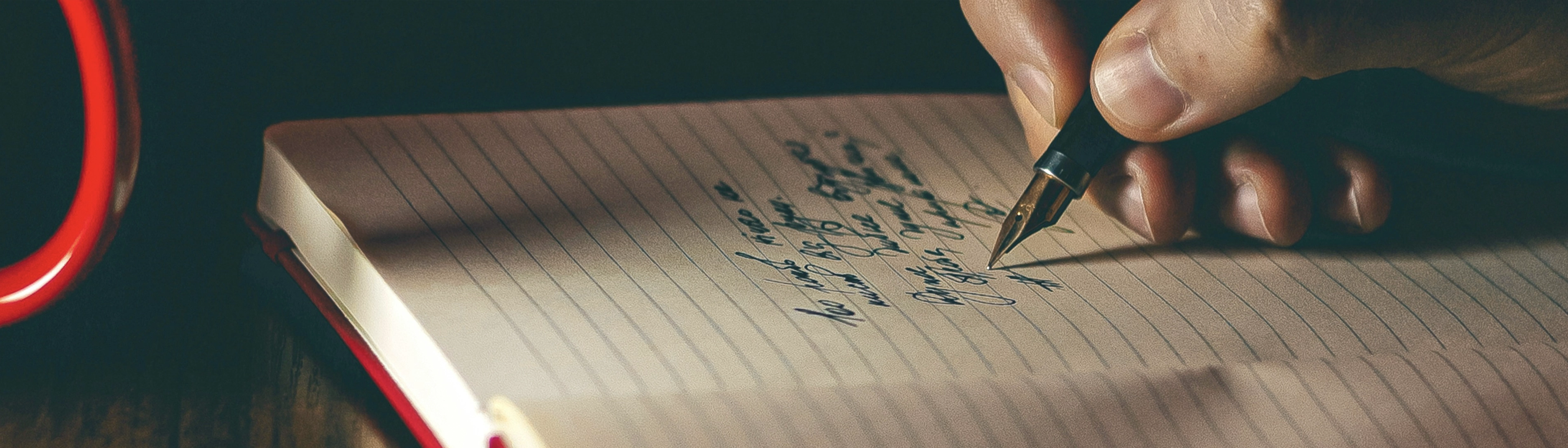 A hand writing in book using a fountain pen.